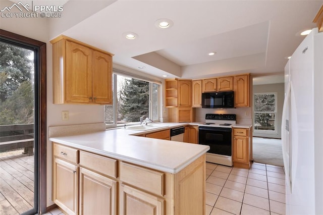 kitchen with black microwave, range with electric stovetop, a sink, freestanding refrigerator, and a raised ceiling