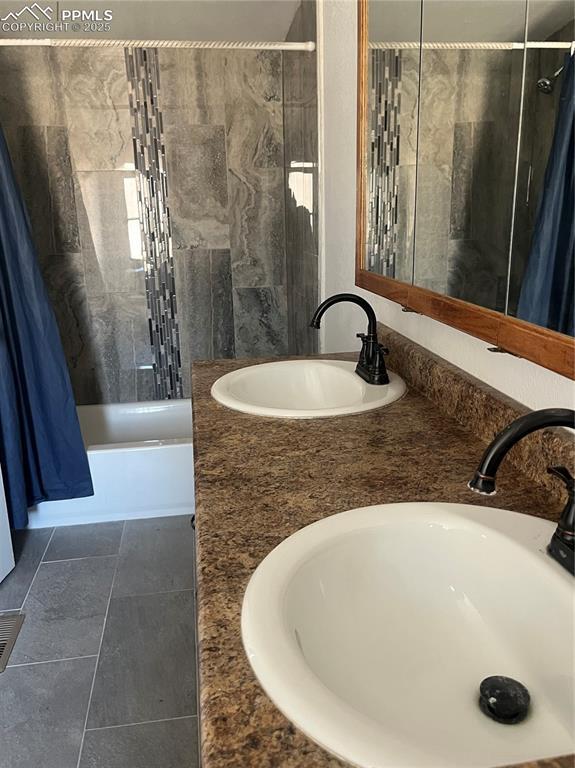 bathroom with double vanity, shower / washtub combination, a sink, and tile patterned floors