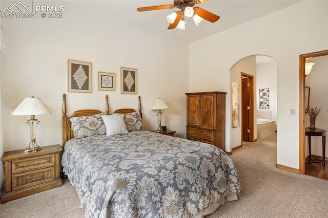 bedroom with arched walkways, ceiling fan, light carpet, and baseboards