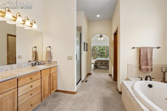 ensuite bathroom with carpet flooring, connected bathroom, vanity, baseboards, and a bath