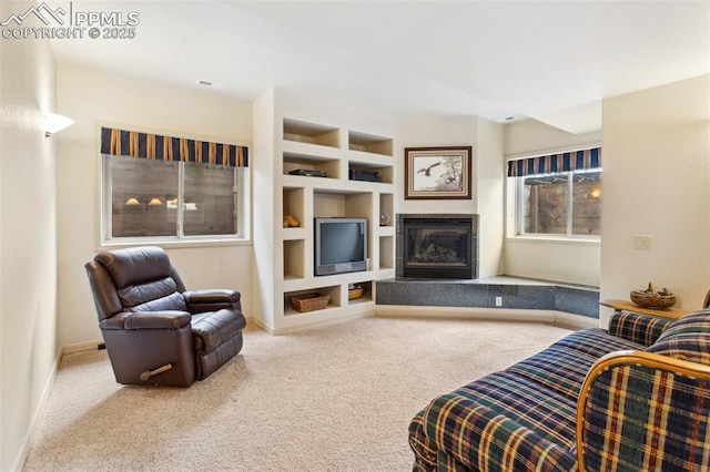 living area featuring a tile fireplace, carpet flooring, visible vents, baseboards, and built in features