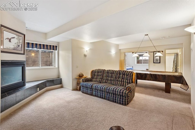 carpeted living area featuring a tile fireplace, pool table, and baseboards