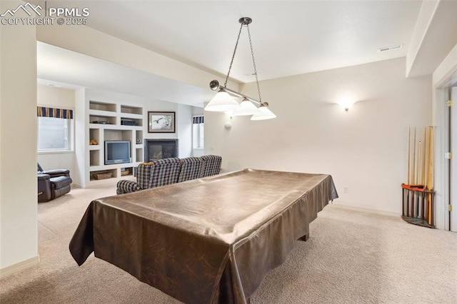 recreation room featuring visible vents, baseboards, built in features, carpet, and a glass covered fireplace