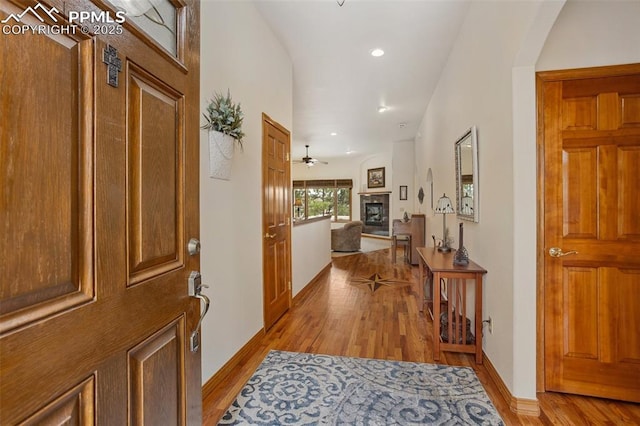 entryway with recessed lighting, a ceiling fan, baseboards, light wood finished floors, and a glass covered fireplace