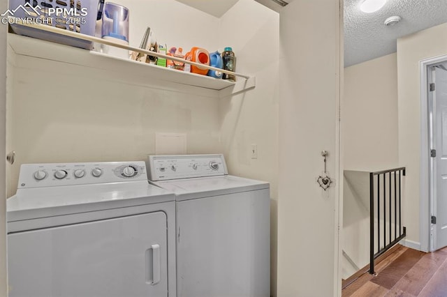 washroom featuring laundry area, wood finished floors, washing machine and dryer, and a textured ceiling