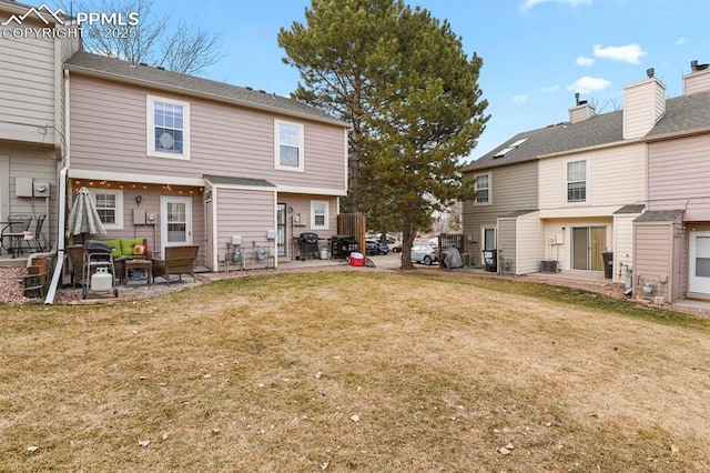 back of house featuring central AC unit, a patio area, and a lawn