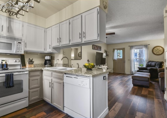 kitchen with dark wood-style floors, open floor plan, white appliances, and a sink