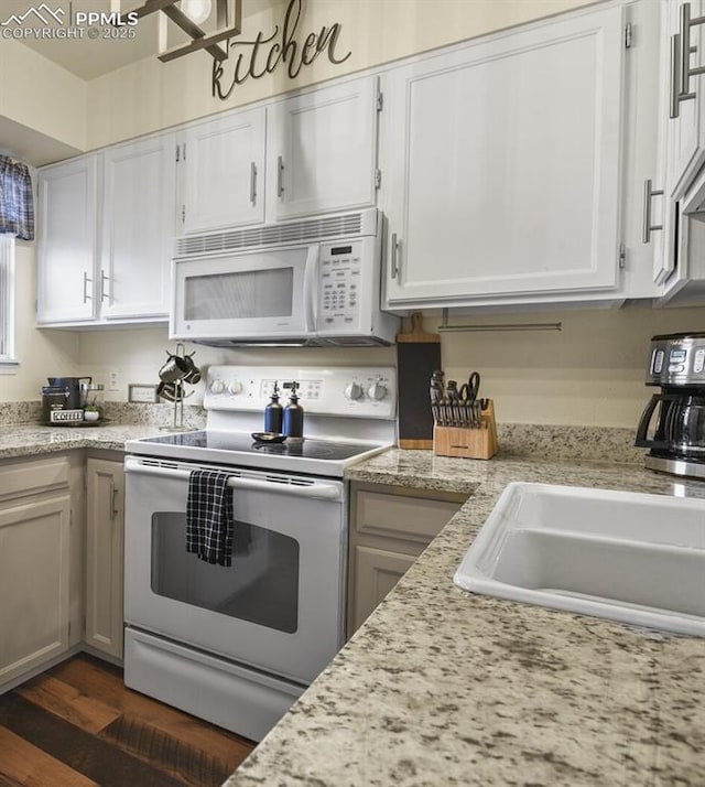 kitchen with dark wood finished floors, white cabinets, white appliances, and a sink