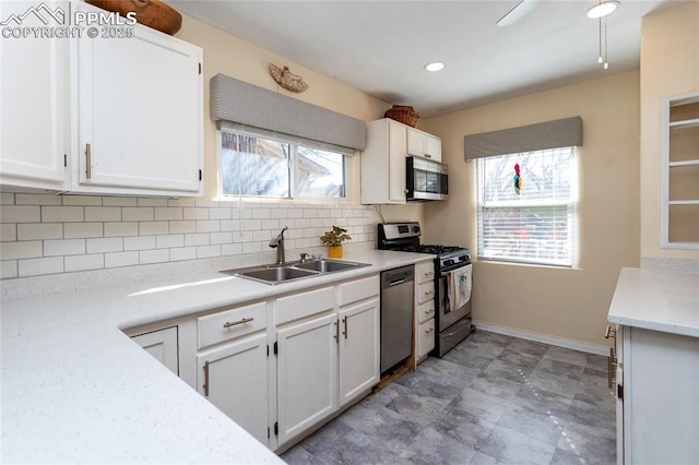 kitchen with a sink, decorative backsplash, light countertops, white cabinets, and stainless steel appliances