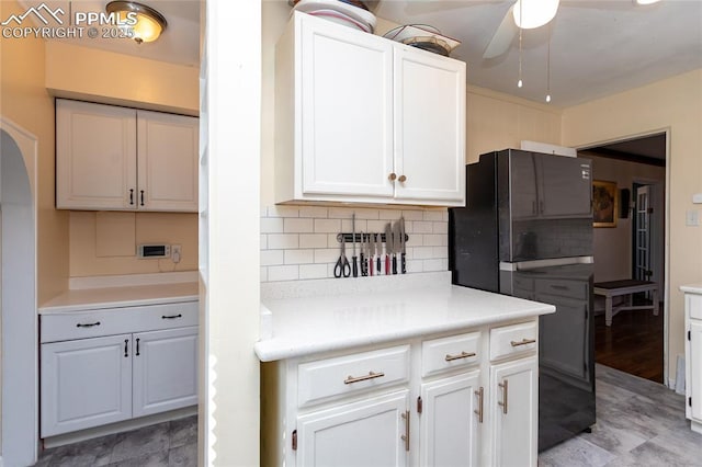 kitchen featuring white cabinetry, light countertops, freestanding refrigerator, and decorative backsplash