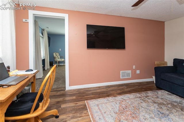 interior space with a ceiling fan, baseboards, wood finished floors, visible vents, and a textured ceiling