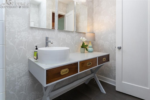 bathroom with wallpapered walls, vanity, and baseboards