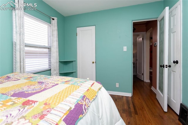 bedroom with wood finished floors, baseboards, and a closet