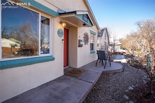 property entrance with stucco siding and a patio