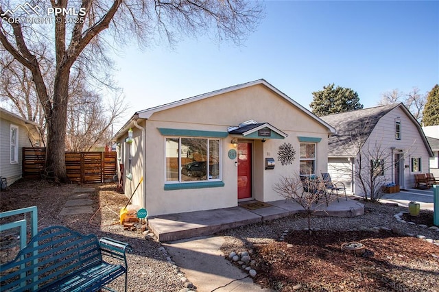 view of front of house with a shingled roof, fence, and stucco siding