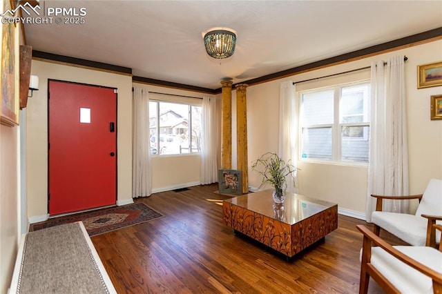 entryway with visible vents, dark wood-type flooring, crown molding, baseboards, and ornate columns