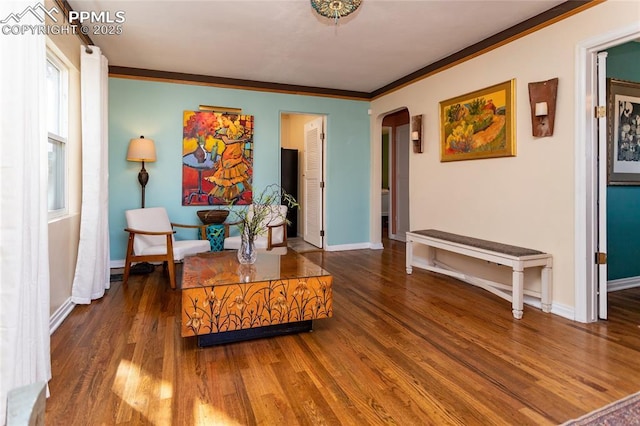 sitting room featuring arched walkways, crown molding, baseboards, and wood finished floors