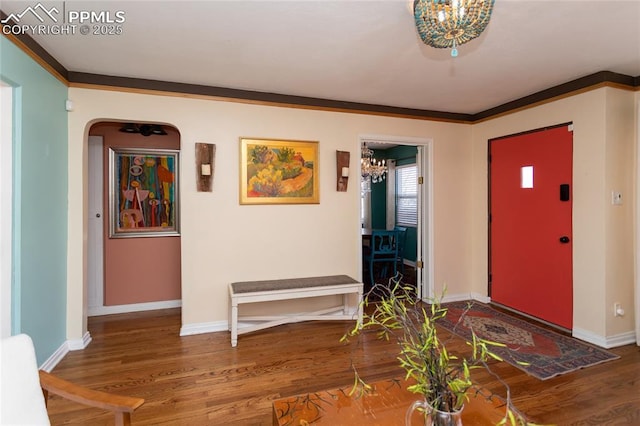 entryway with crown molding, wood finished floors, baseboards, and arched walkways