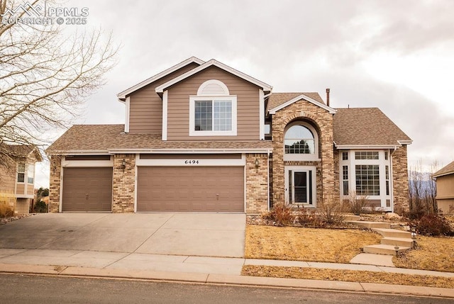 traditional-style house featuring concrete driveway, brick siding, and a shingled roof