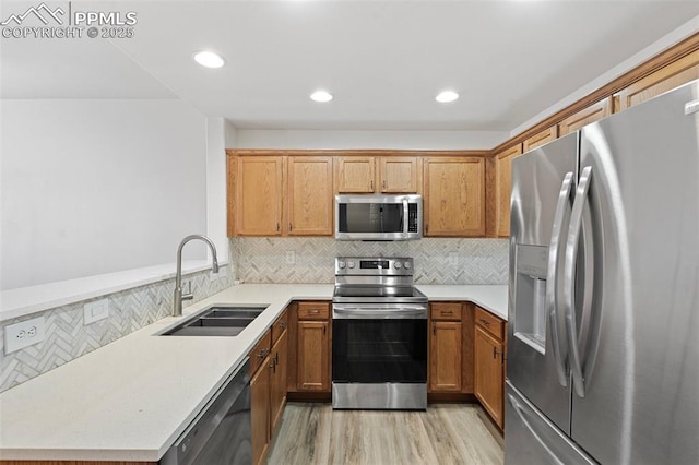 kitchen with decorative backsplash, a peninsula, stainless steel appliances, light wood-type flooring, and a sink