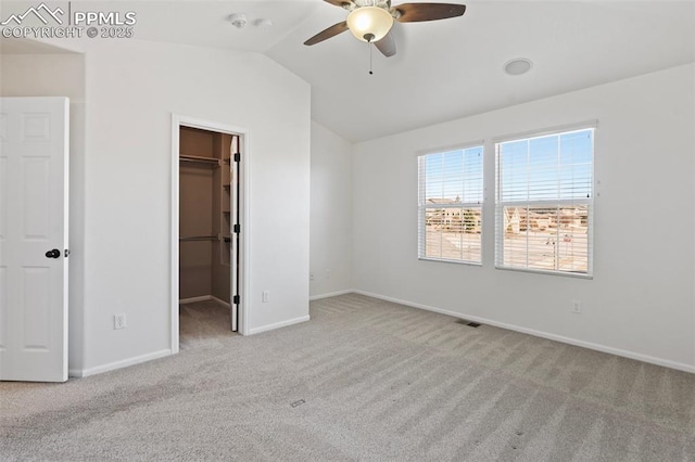 unfurnished bedroom featuring vaulted ceiling, carpet flooring, a walk in closet, and visible vents