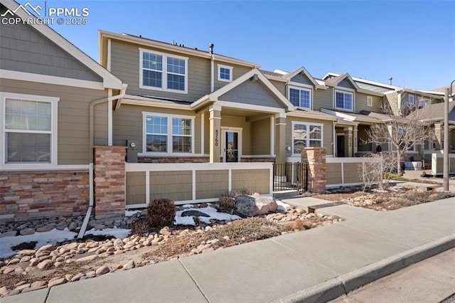 view of front of home featuring stone siding, a fenced front yard, and cooling unit