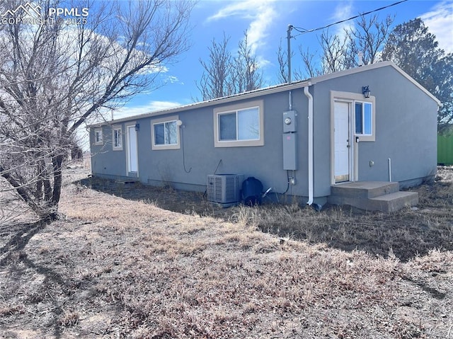 back of house featuring central AC unit and stucco siding