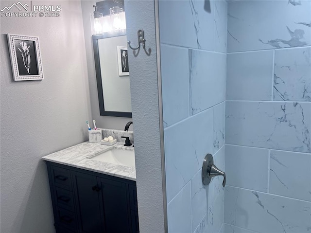 bathroom with tiled shower and vanity