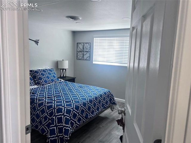 bedroom featuring visible vents, baseboards, and wood finished floors