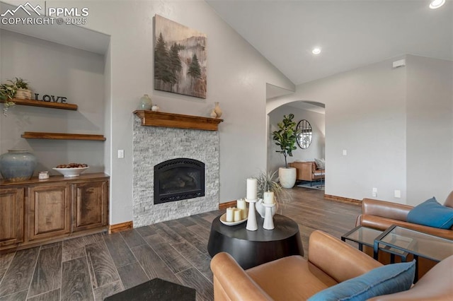 17820 Pioneer Xing, Colorado Springs, CO 80908 - living area with arched walkways, dark wood-style floors, vaulted ceiling, a stone fireplace, and recessed lighting