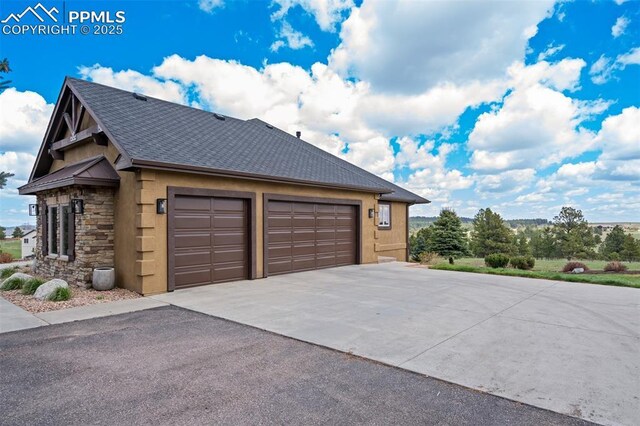 17820 Pioneer Xing, Colorado Springs, CO 80908 - view of home's exterior featuring stone siding, roof with shingles, driveway, an attached garage, and stucco siding