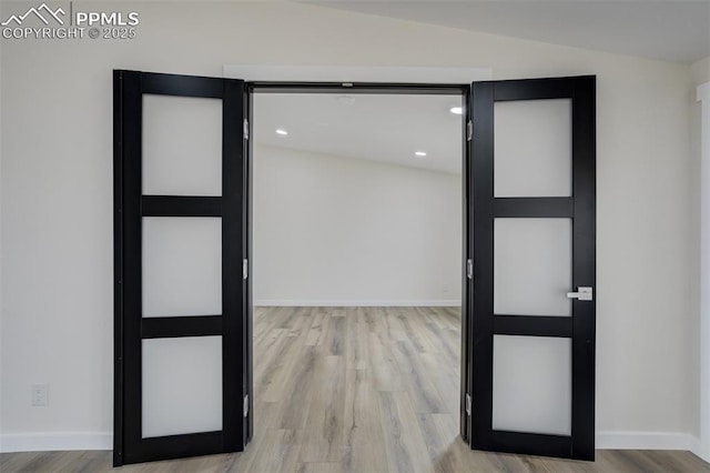 interior space with lofted ceiling, baseboards, and light wood finished floors