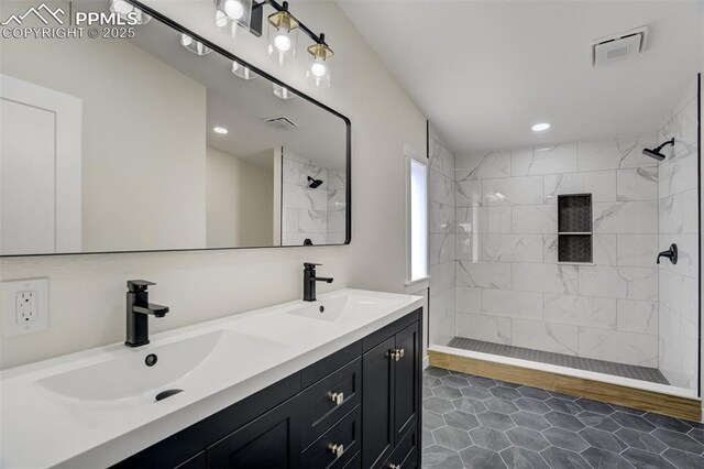 bathroom featuring double vanity, tiled shower, visible vents, and a sink