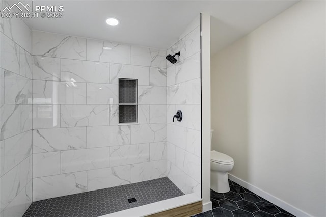 full bath featuring tile patterned flooring, toilet, baseboards, and a tile shower