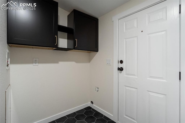 laundry area with dark tile patterned floors, cabinet space, electric dryer hookup, and baseboards