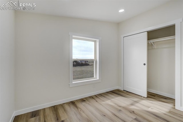 unfurnished bedroom with recessed lighting, a closet, baseboards, and wood finished floors