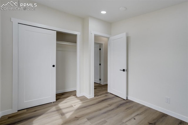 unfurnished bedroom with a closet, recessed lighting, baseboards, and wood finished floors