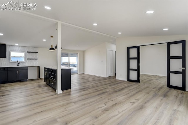 kitchen with dark cabinetry, light wood-style floors, light countertops, and a sink