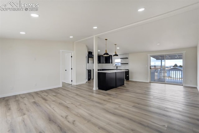 kitchen featuring lofted ceiling, light wood-style flooring, light countertops, and open floor plan