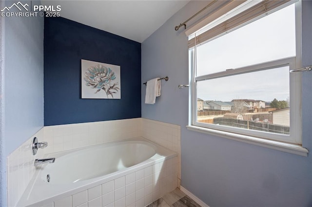 full bathroom featuring a bath and baseboards