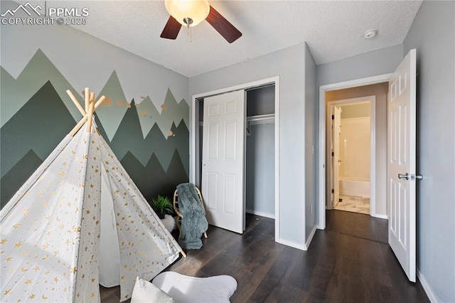 bedroom with a closet, ceiling fan, a textured ceiling, wood finished floors, and baseboards