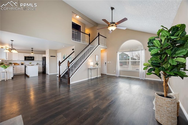 unfurnished living room with dark wood finished floors, ceiling fan, a textured ceiling, baseboards, and stairs