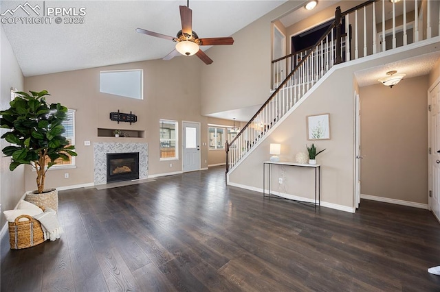 unfurnished living room featuring wood finished floors, a fireplace, baseboards, and stairs