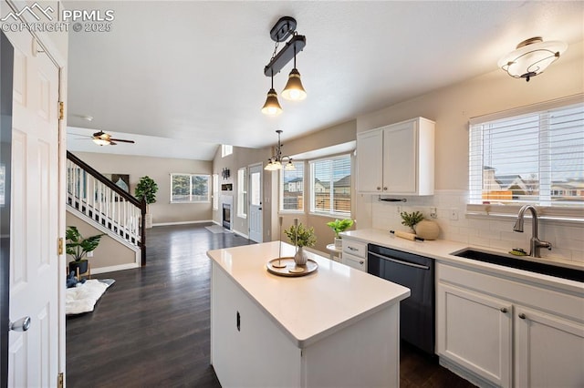 kitchen featuring dishwasher, a kitchen island, backsplash, open floor plan, and a sink