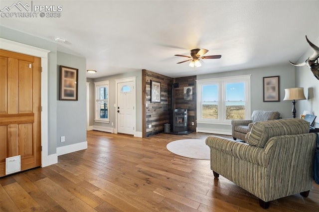 living room with a wealth of natural light, hardwood / wood-style floors, a wood stove, and baseboards