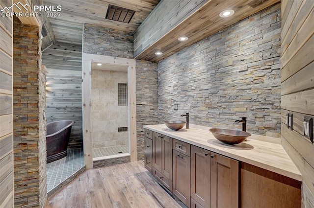 bathroom featuring double vanity, visible vents, a stall shower, a sink, and wood finished floors