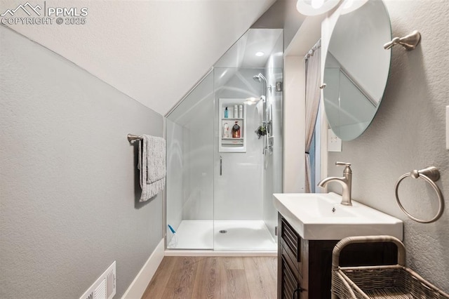 full bath featuring a stall shower, vanity, wood finished floors, and a textured wall