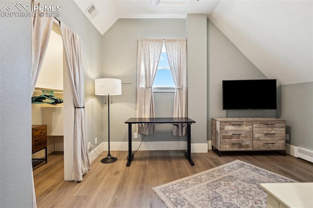 living area with lofted ceiling, baseboards, visible vents, and wood finished floors