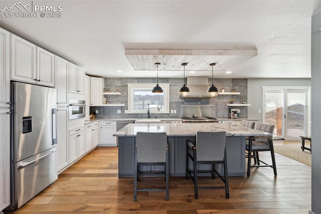 kitchen featuring open shelves, plenty of natural light, stainless steel appliances, and light wood-style flooring