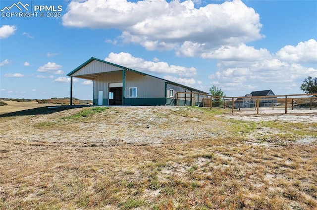 back of property with fence, an outdoor structure, and an outbuilding